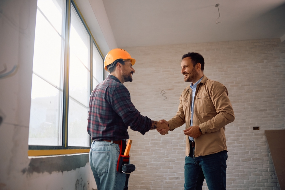 Happy manual worker greeting his client at construction site